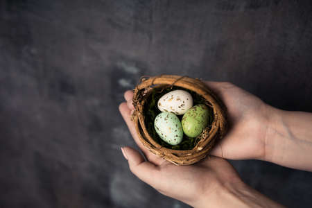 Three colorful easter eggs in a basket on a brown wood. High quality photo