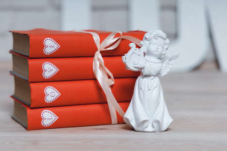 White angel with a violin with red books with the word Love. High quality photo