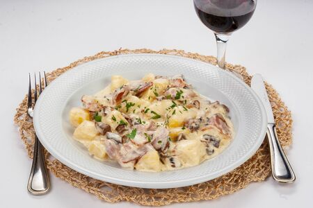 Potato stew with mushrooms and bacon in sour cream sauce and glass of vineの写真素材
