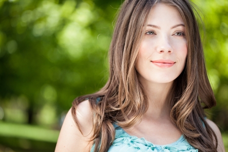 Close-up portrait of a beautiful Caucasian young woman on a spring sunny day in park. Looking away.の写真素材