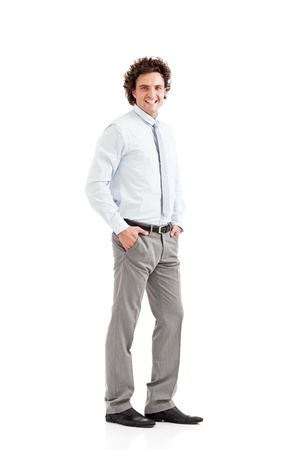 Smiling young businessman with hands in pockets looking at camera on white background の写真素材