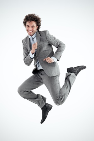 Young businessman excitedly jumps into the air in celebration  Vertical shot  Looking at camera の写真素材