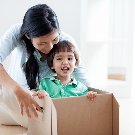 Young mother playing with her son who is in a cardboard box.の写真素材