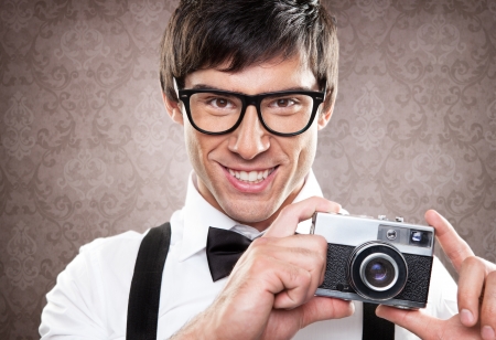 A young handsome man holding an old camera and smiling.の写真素材
