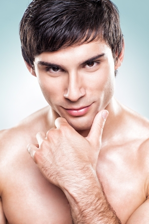 A young handsome man posing shirtless in front of a blue background.の写真素材