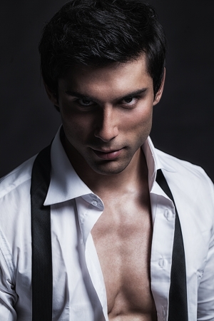 A handsome male model posing at a studio in front of a black background.の写真素材