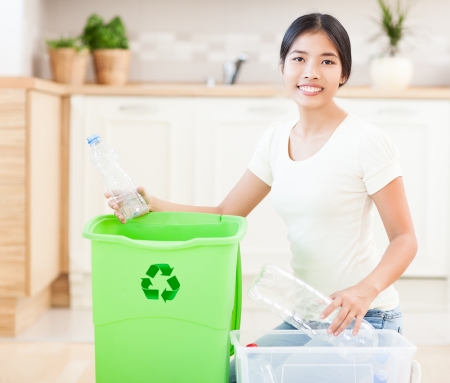 Young Asian woman with a crate full of plastic bottles for recycling.の写真素材