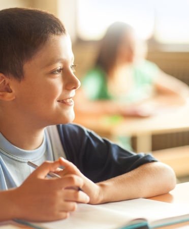 A boy sitting at his desk at school.の写真素材