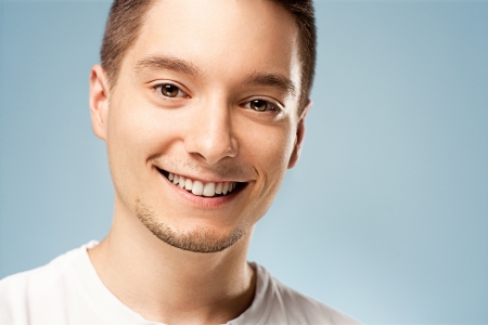 A young man smiling and posing in front of a blue background.の写真素材