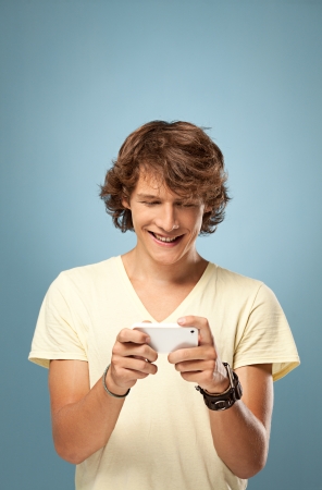 A smiling young man sending a text message.の写真素材