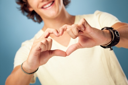 Young man making a heart shape with his hands.の写真素材