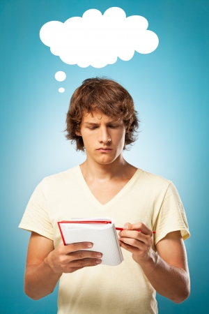 Worried young man holding a notebook and writing something.の写真素材