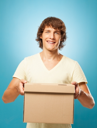 Young man holding a cardboard box and smilingの写真素材
