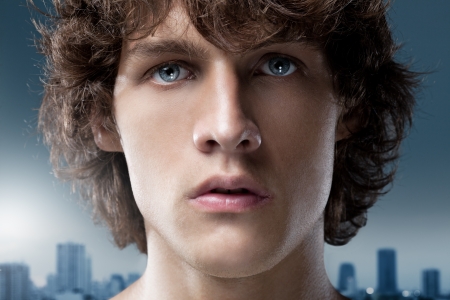 Blue-eyed young man in front of the outline of a big city.の写真素材