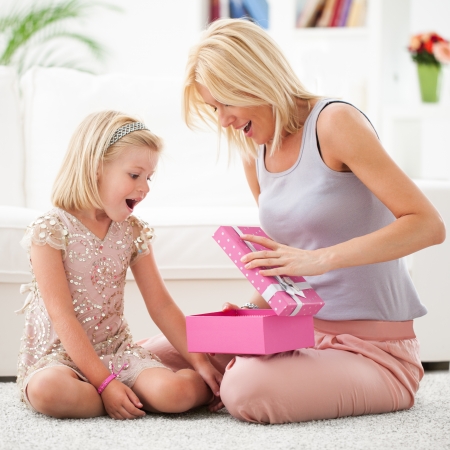Mother and her daughter opening a pink birthday present.の写真素材