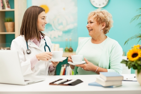 Smiling doctor drinking tea and talking to her patient.の写真素材