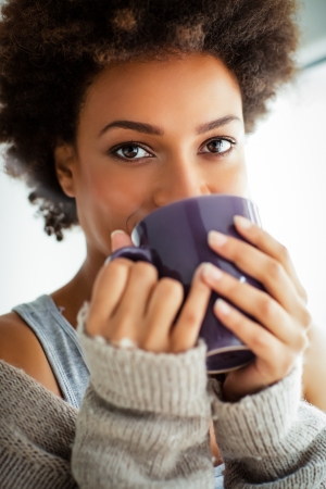 Beautiful young African woman enjoying a cup of coffee.の写真素材