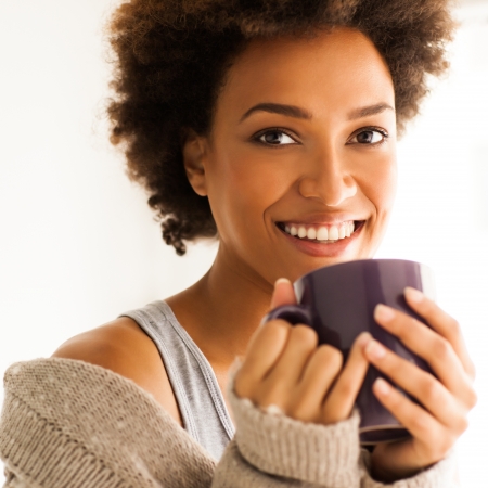 Beautiful young African woman enjoying a cup of coffee.の写真素材