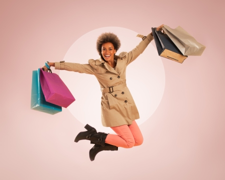 Young African woman jumping with shopping bags in her hands.の写真素材