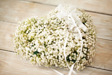 Heart-shaped wedding flower arrangement with wedding rings on it.の写真素材