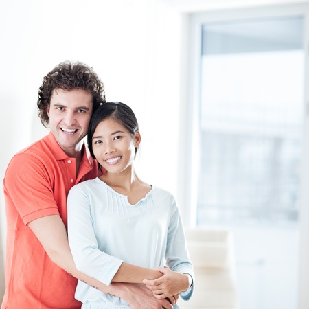 Happy young couple standing and posing in their new apartment.の写真素材