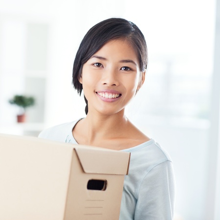 Beautiful young Asian woman carrying a cardboard box.の写真素材