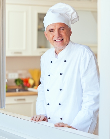 Smiling senior chef in his kitchen.の写真素材