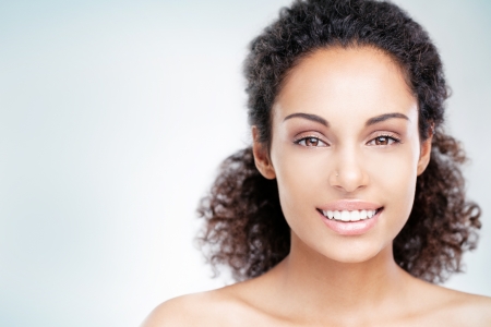 Young African woman smiling and posing in front of a blue background.の写真素材