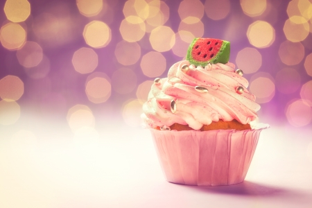 Delicious pink cupcake in front of a glittering purple background.の写真素材