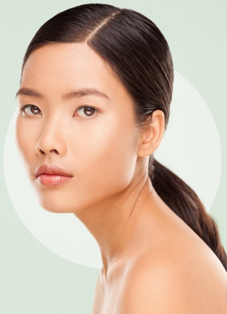 Beautiful young Asian woman posing against a green background.の写真素材