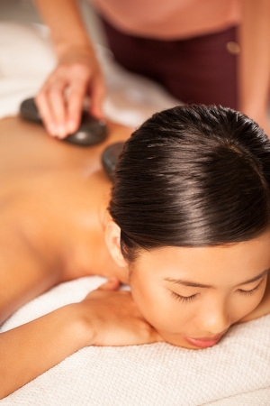 Asian woman enjoying a hot stone treatment.の写真素材