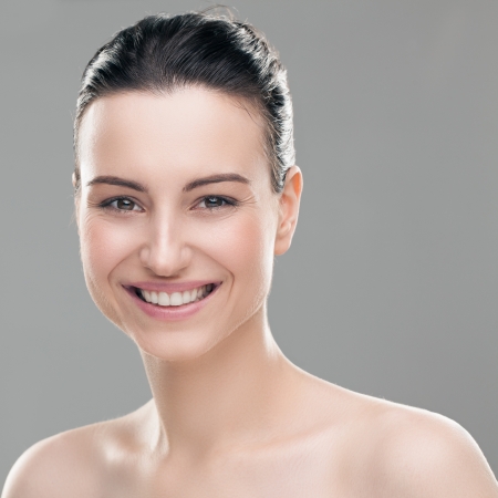 Portrait of a smiling Caucasian woman posing topless against a gray background.の写真素材