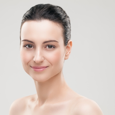 Portrait of a smiling Caucasian woman posing topless against a gray background.の写真素材