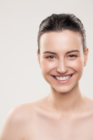 Portrait of a smiling Caucasian woman posing topless against a gray background.の写真素材