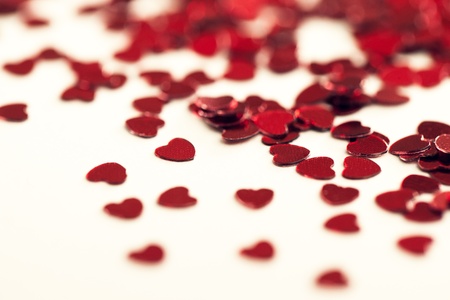 Heart-shaped confetti on a white surface in close-up.の写真素材