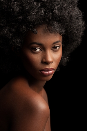 Beautiful young African woman posing against a black background.の写真素材