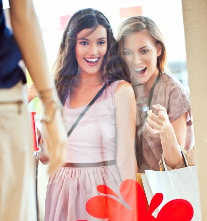 Two beautiful women looking surprisedly at something in the clothing store window.の写真素材