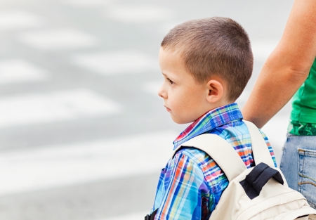 A cute little boy and his mother waiting to cross the street on their way to school.の写真素材