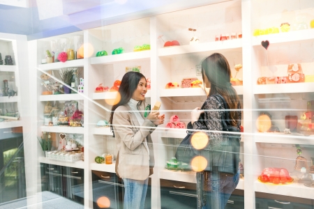 Two smiling women at the soap shop seen through the shop window.の写真素材