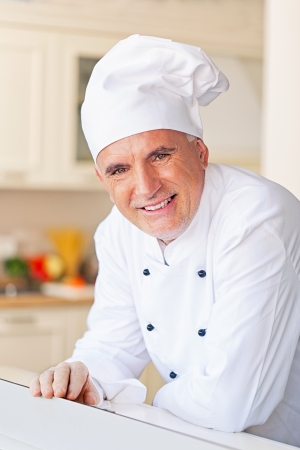 Smiling senior chef in his kitchen.の写真素材