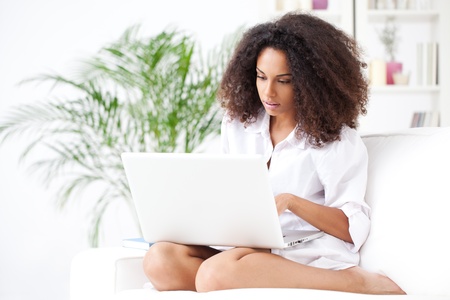 Young African woman using her laptop in her living room.の写真素材