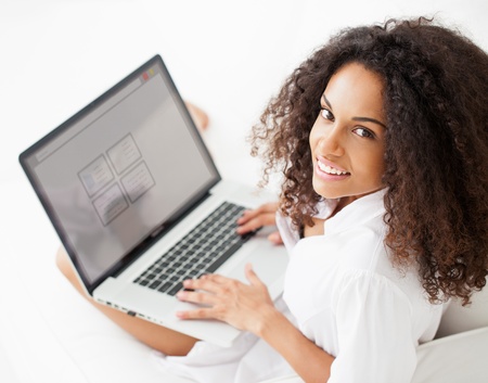 Smiling African woman working on her laptop at home.の写真素材