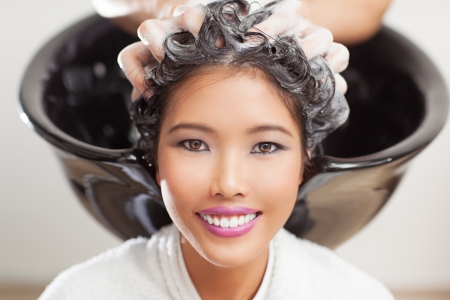 Smiling Asian woman having her hair washed at the hairdresser's.の写真素材