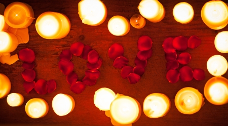 Rose petals forming the word 'love' surrounded by white candles.の写真素材