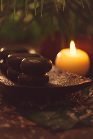 Hot stones and a lit candle used for spa treatments in a tropical setting.の写真素材