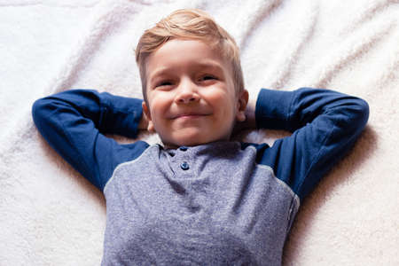 Cute happy kid relaxing on the bed.