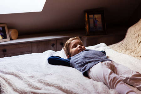Little boy lying on the bed and napping at home.の写真素材
