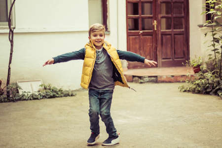 Carefree boy playing outdoors and spinning with arms outstretched.の写真素材
