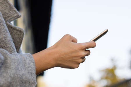 Close up of woman using cell phone and typing text message.の写真素材