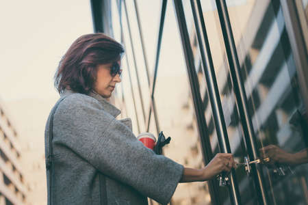 Beautiful woman unlocking door with a key and entering in residential building.の写真素材